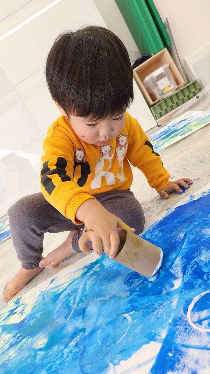 青い絵の具でアート活動をする子ども